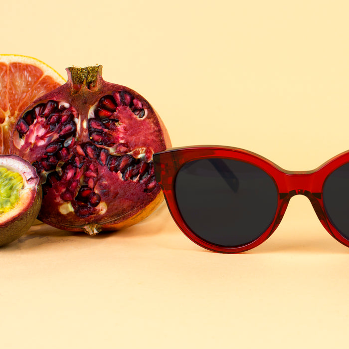 Some sunglasses next to a sliced pomegranate