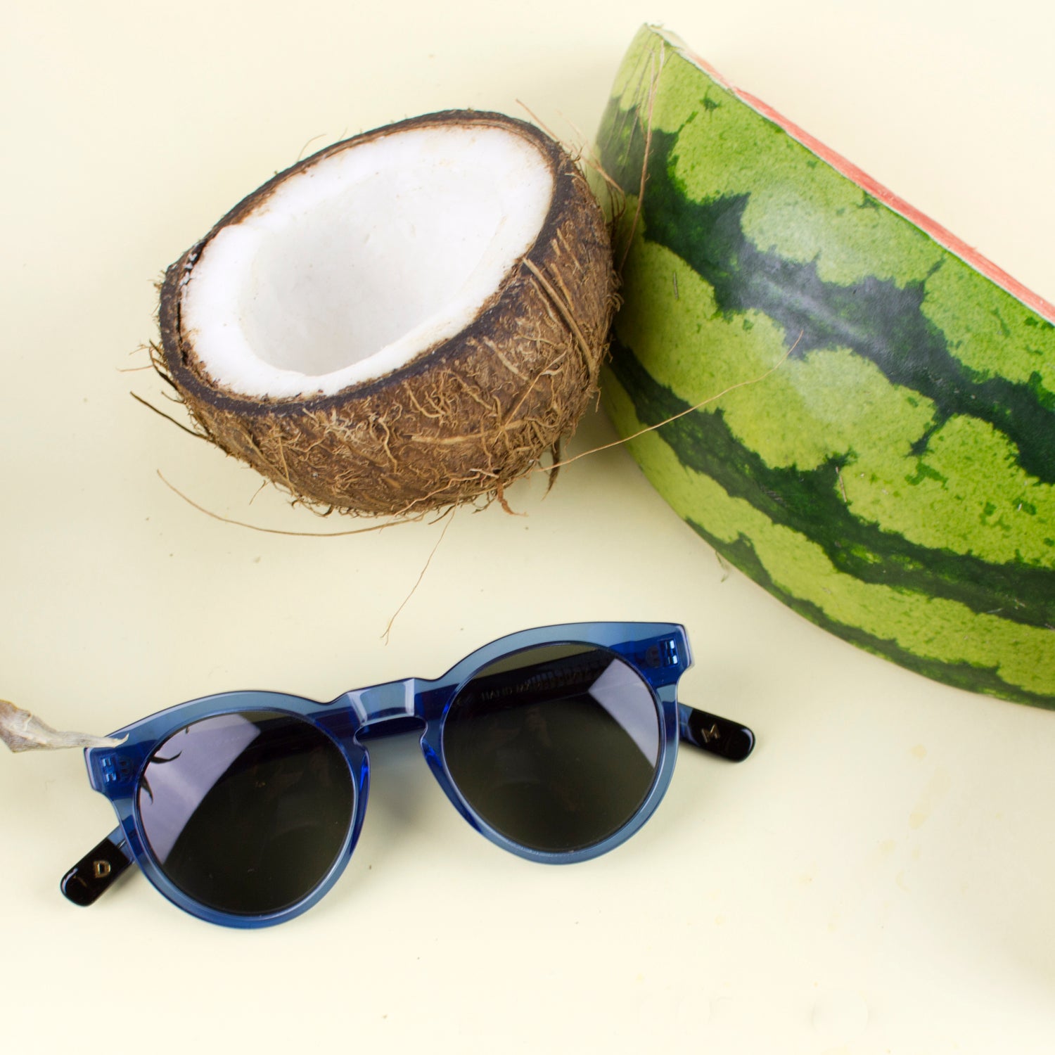 Sunglasses next to a coconut and watermelon