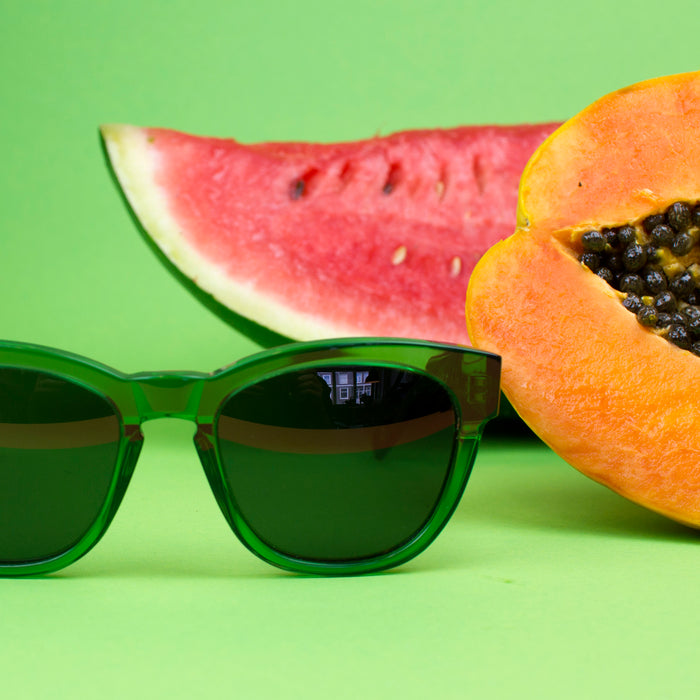 Green frame sunglasses next to fruit.