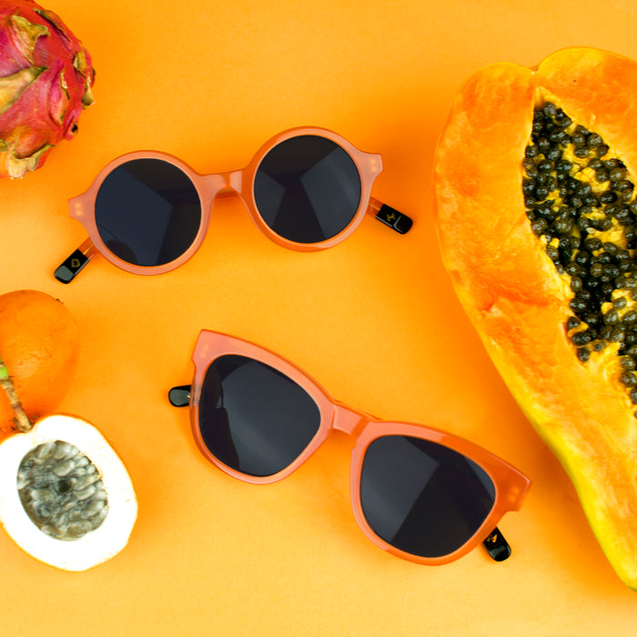 Orange sunglasses next to a papaya